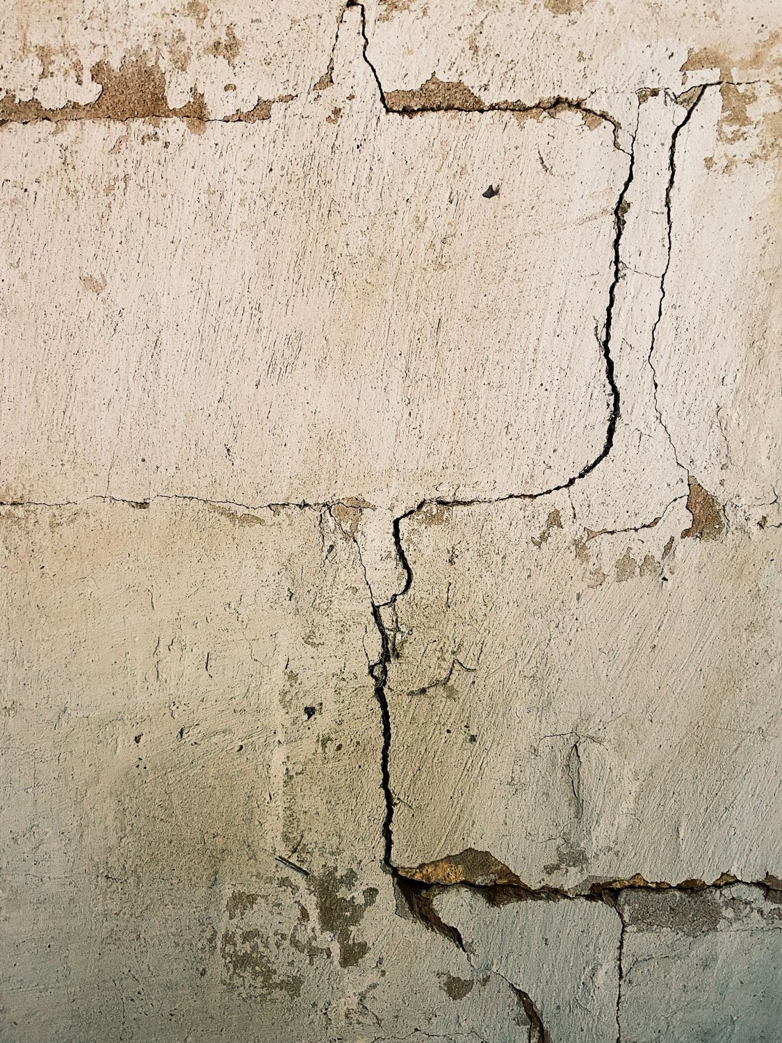 Stair-step crack running through a rendered masonry wall